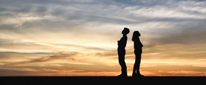 man and woman standing not facing each other, may be contemplating divorce